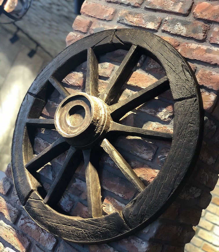 Faux Wood Wagon Wheel Mounted on Brick Pillar