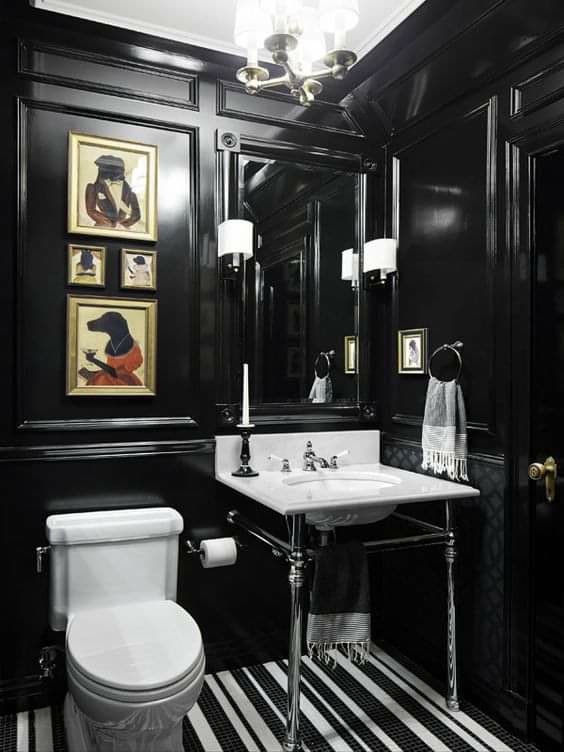 Glossy black bathroom with box trim moldings, aristocratic dog portraits, a chrome console sink, and black-and-white striped flooring.