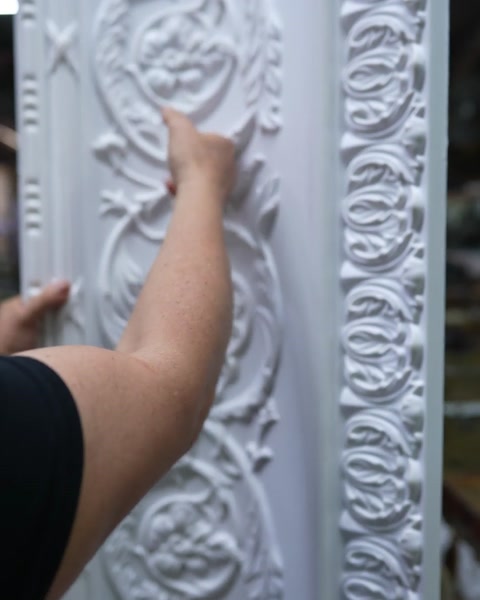 Fingertips trace deep undercut ornament on unfinished cornice surface
