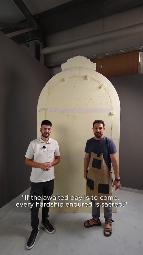 Dois artesãos inspecionam um molde de arco em bruto, por acabar.
