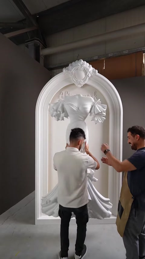 Trabalhadores montam a peça de relevo esculpido do vestido no painel do arco.