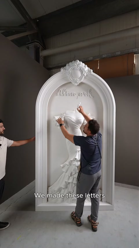 Artesão ajusta um caractere de letra individual acima do relevo de vestido montado.
