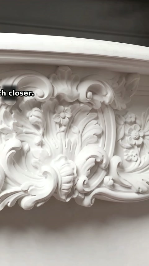 Tiefe Formdetails mit floralen Mustern füllen die zentrale Krone des weißen Mantels.