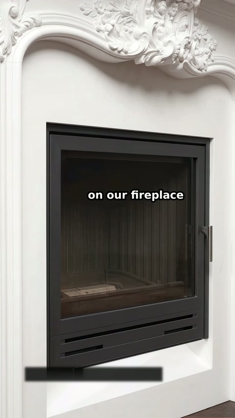 Der schwarze Feuerraum sitzt unter einer gewölbten Öffnung mit floraler Dekoration.