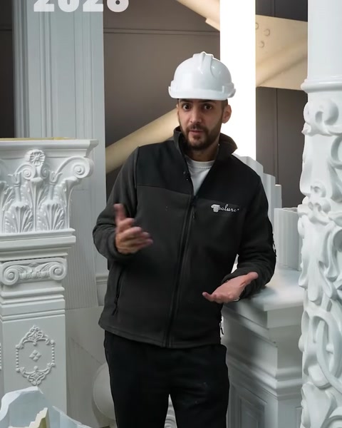 Staff member explains carved polyurethane columns inside factory showroom