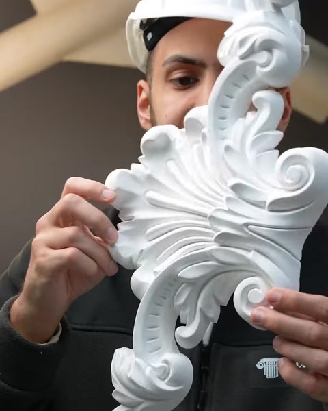 Close-up hands holding detailed white polyurethane acanthus scroll