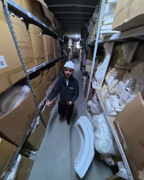 Employee walks past shelves holding white polyurethane column pieces
