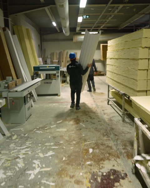 Un trabajador transporta láminas de material de poliuretano en bruto por el almacén