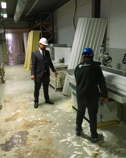 Un trabajador camina hacia una máquina de corte de poliuretano en el taller