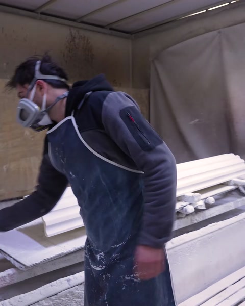 Un trabajador con mascarilla pinta con pistola la base de una columna de poliuretano