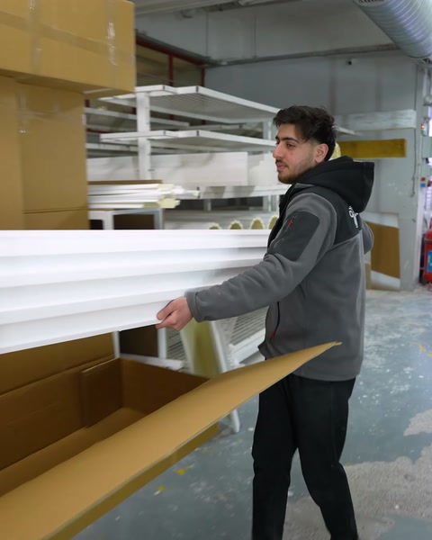 Un trabajador empaqueta un perfil de poliuretano terminado en una caja de cartón