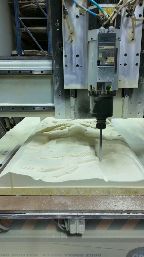 Une machine CNC grave un relief floral complexe dans un panneau de production