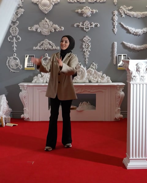 Presenter gesturing beside a fireplace with cornice wall decor
