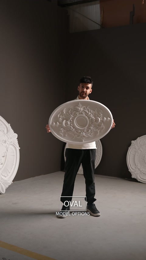 Le présentateur tient un médaillon de plafond ovale orné d’un décor floral équilibré.