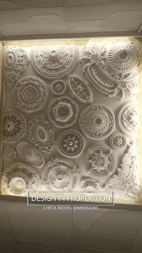 Un mur d’exposition présente de nombreux médaillons de plafond aux formes et dimensions variées.