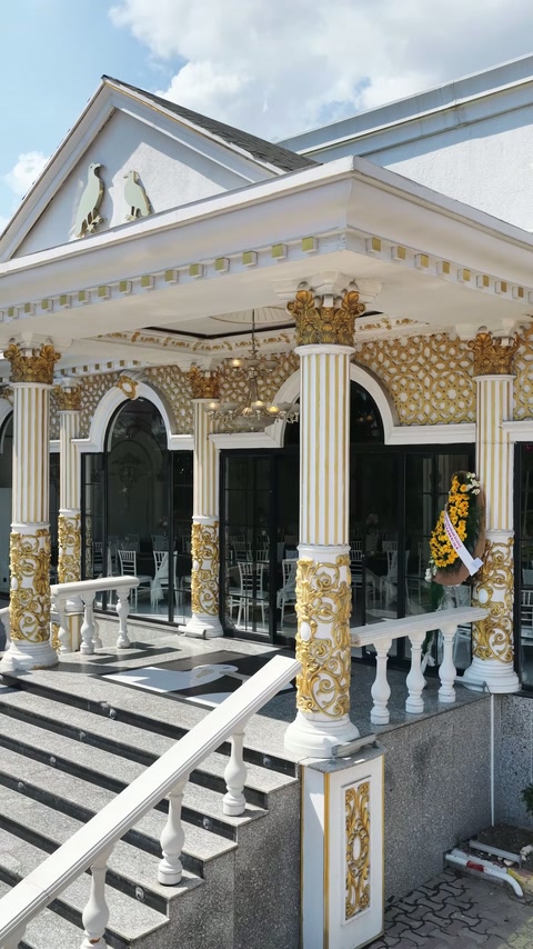 Der Außeneingang besitzt kannelierte Säulen, Kapitelle und dekorative goldene Reliefs