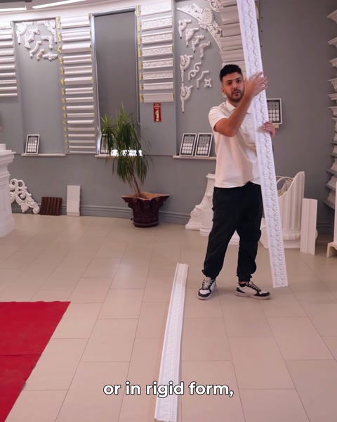 Presenter holds a straight rigid moulding upright in the showroom