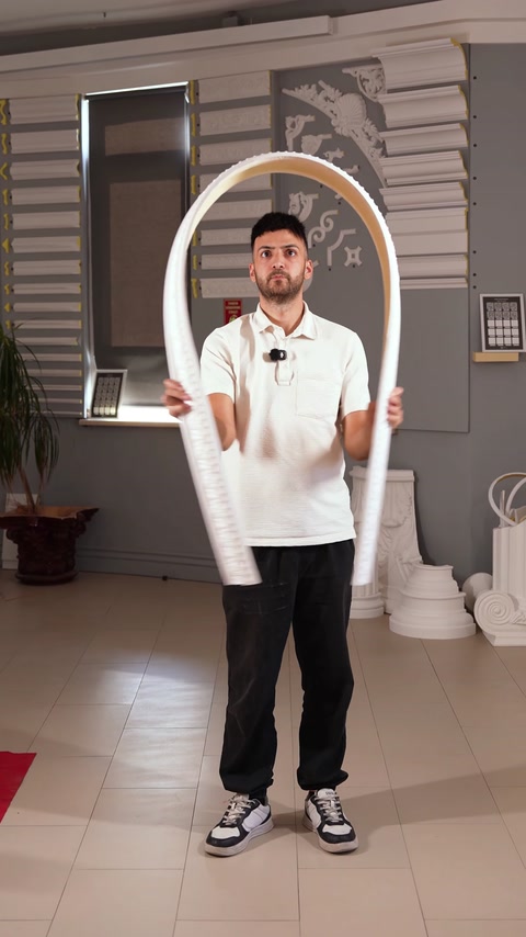 Presenter holds a curved decorative border moulding for showroom demonstration