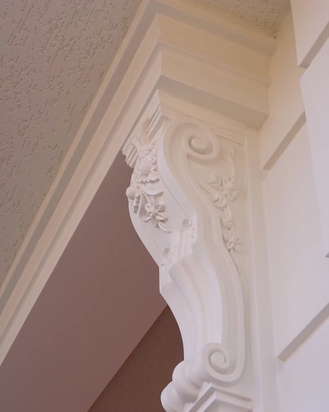 Detailní pohled na dekorativní konzolu podporující zakřivený roh architra