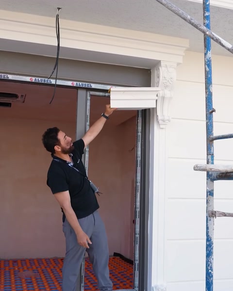 Instalatér umisťující korunní nátěr nad otvor okna na lešení