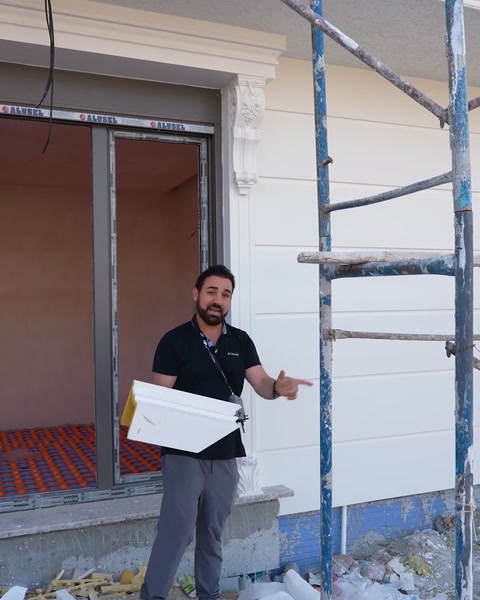 Muž nesoucí část nátěru u okna během instalace