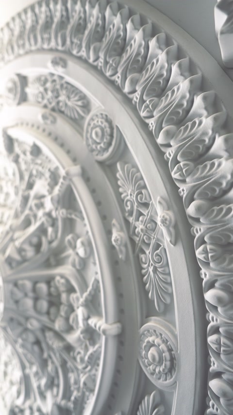 Gros plan sur un médaillon de plafond sculpté avec un détail de feuille d’acanthe