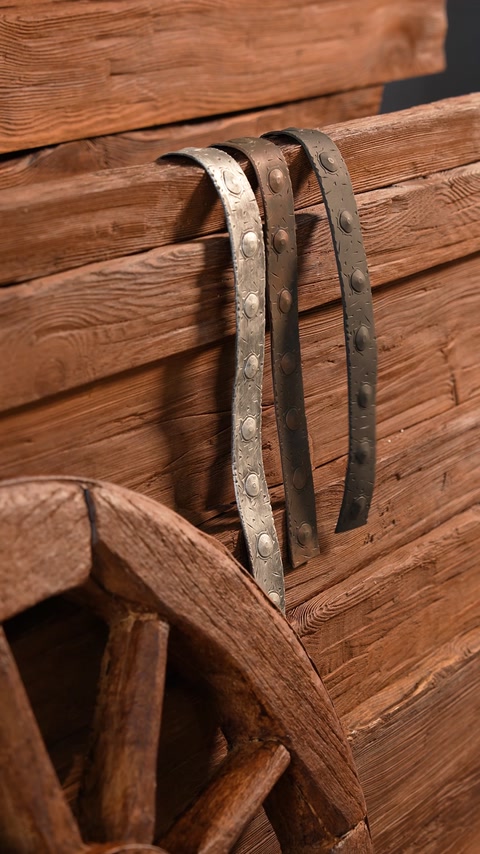 Roue de charrette avec brides métalliques contre une poutre en bois