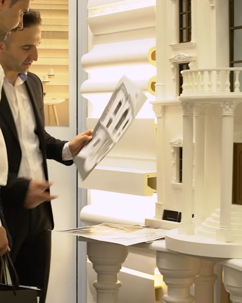 Man holding decorative cornice sample panel at exhibition booth