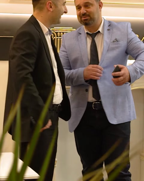 Two men in suits conversing near decorative column display