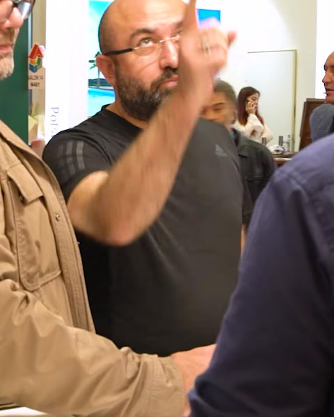 Man gesturing while talking at exhibition stand entrance