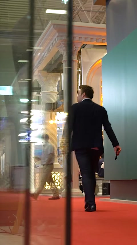 Mand der går forbi oplyst glaspaneldisplay på messen