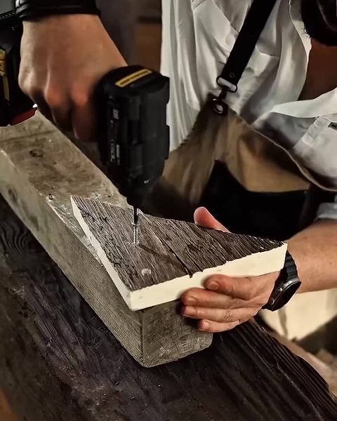 Close-up of drill fastening corner joint on textured beam