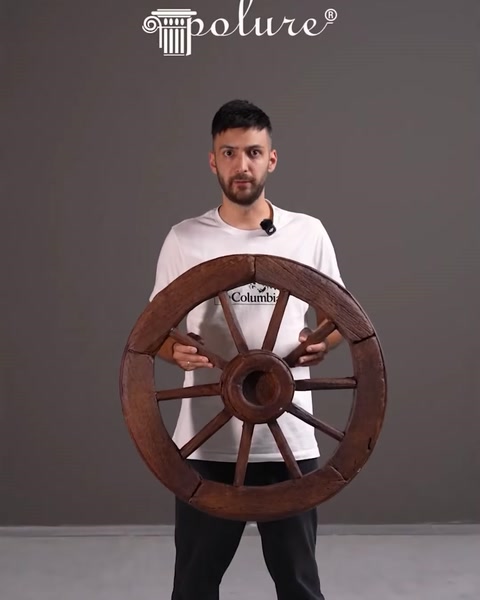 Il presentatore tiene in mano una grande ruota decorativa in stile legno