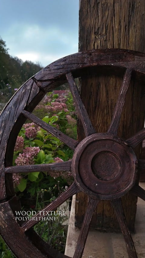 Roue rustique en polyuréthane et poteau aspect bois exposés dans un jardin.