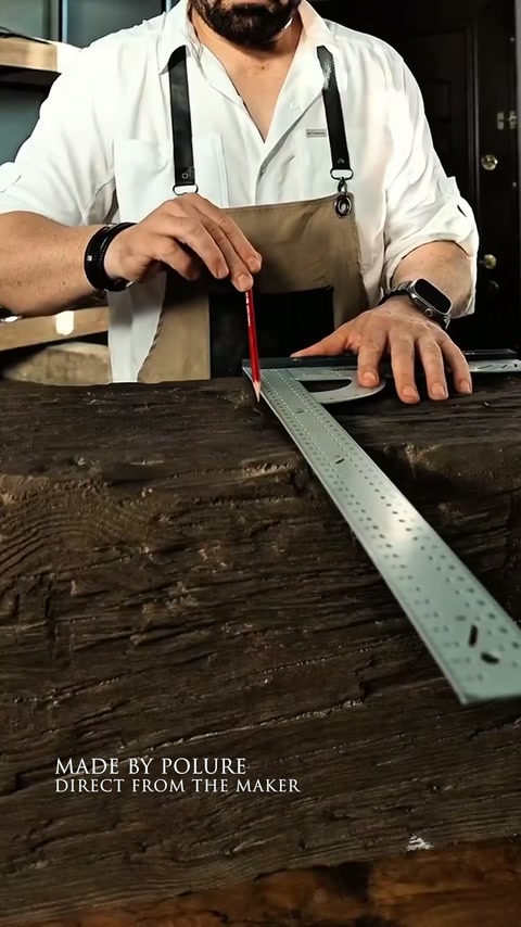 Un artisan mesure une poutre décorative avant les travaux de coupe ou d’ajustement.