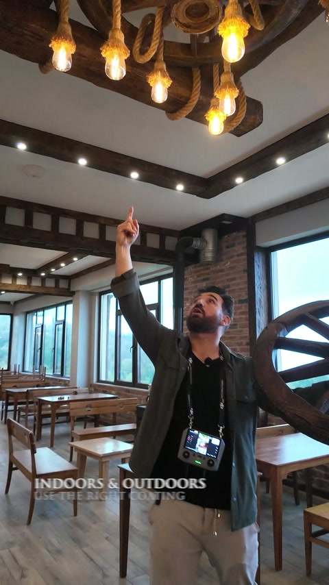 Des poutres imitation bois et des luminaires en roue de chariot décorent le plafond d’un restaurant spacieux.