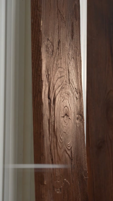Un poteau décoratif vertical présente une texture continue de veinage de bois sculpté.