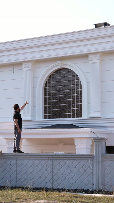 Eine Bogenumrahmung des Fensters und horizontale Profile gliedern die weiße Fassade.