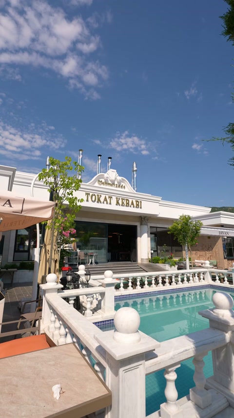 Dekorative Balustraden und Gesimse verbinden die Fassade des Objekts am Pool zu einem einheitlichen Gesamtbild.