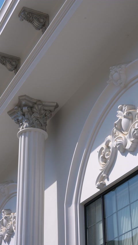 Eine volutenförmige Fensterbekrönung trifft unterhalb des Gesimses auf eine kannelierte Säule.