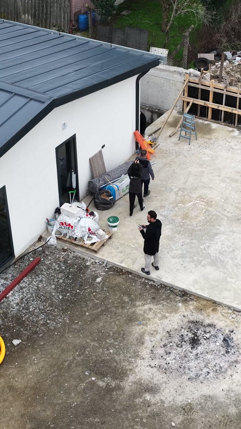 Une vue plongeante présente l’activité de relevé à côté du bâtiment achevé.