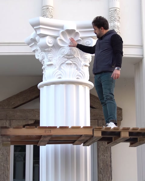 Pracovník stojí vedle plně smontovaného sloupu s nainstalovanou hlavicí.