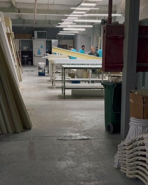 Long hall d'usine avec établis et profilés empilés par longueur
