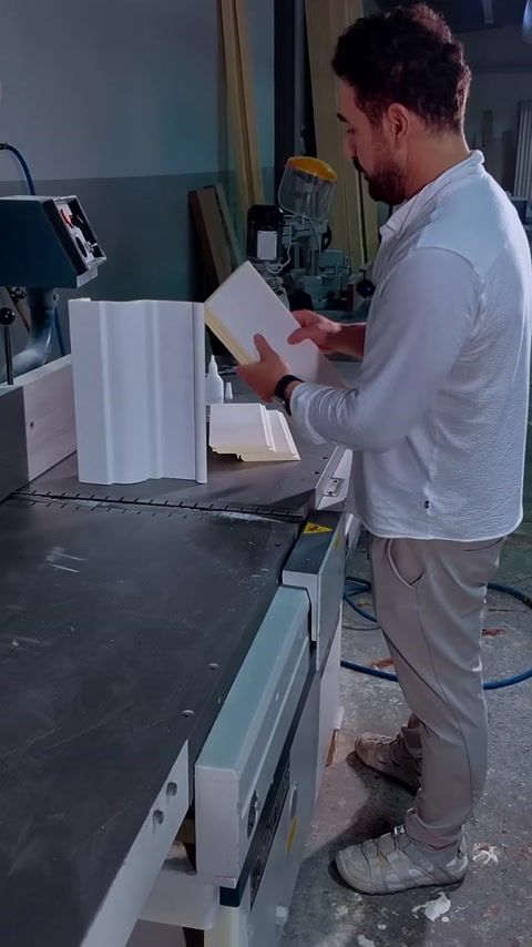 Een medewerker controleert twee kroonlijstlengtes op de juiste hoekverbinding