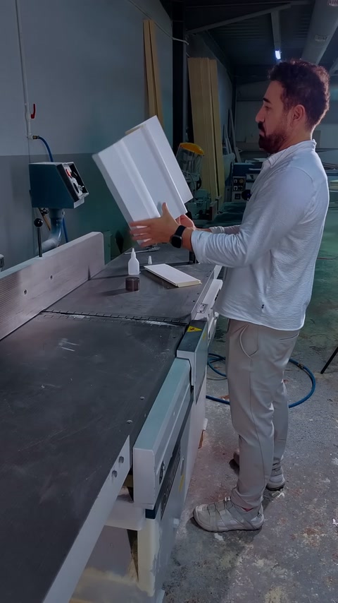 Vakman houdt de gemonteerde listhoek rechtop naast de werkplaatszaag.