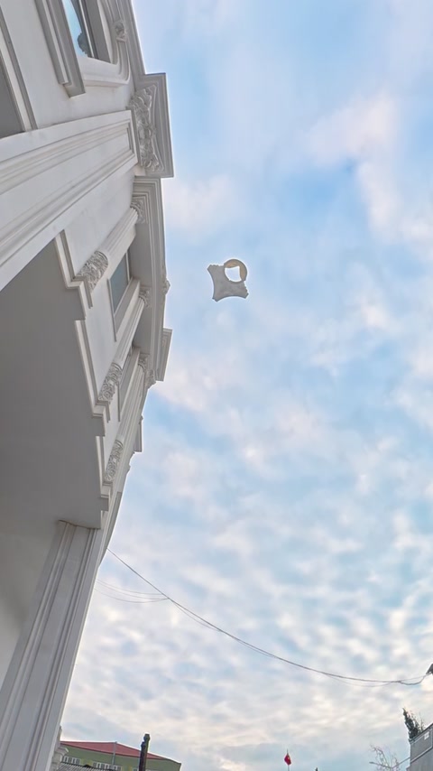 Dekorativní polyuretanový prvek je během zkoušky pádem zachycen ve vzduchu mezi budovami.