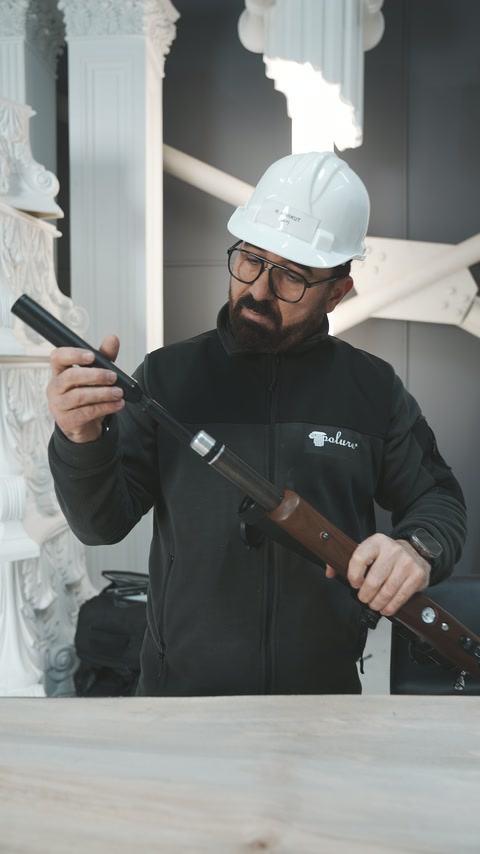 Il-worker jesamina l-mekkaniżmu tal-rifle miftuħ ġewwa l-showroom.
