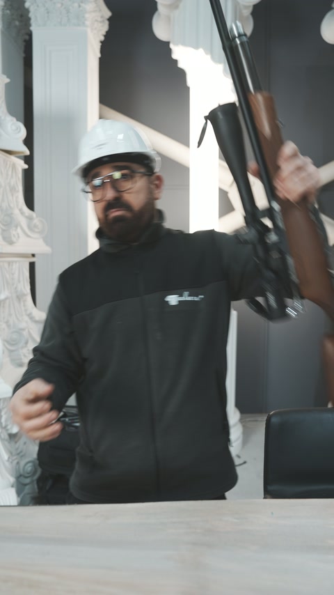 Il-worker jirfa' l-rifle magħluq fost kolonni u kirisi dekorattivi.