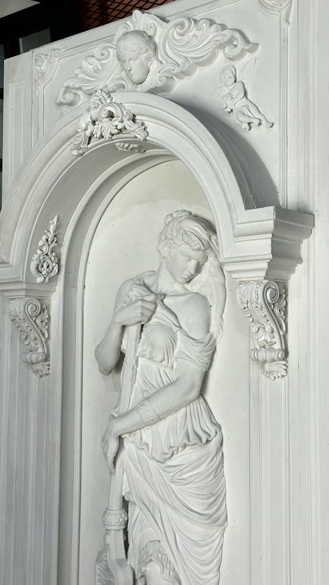 Detailní záběr ukazuje drapovanou postavu uvnitř zdobné klenuté niky