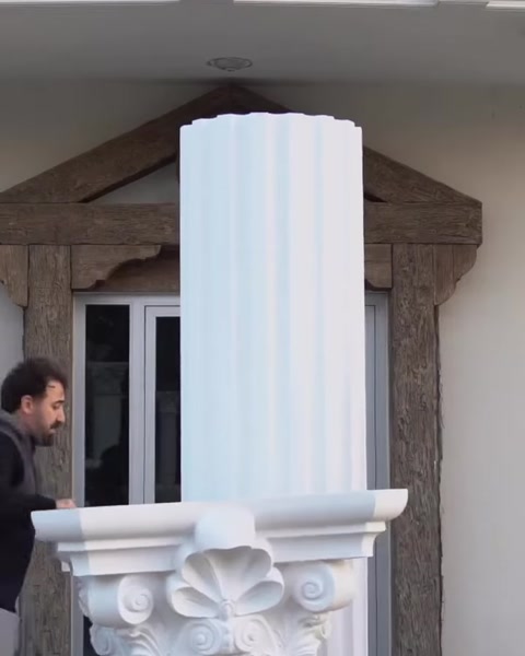 Monteur positioniert Kapitellstück nahe Säulentop an Fassade.